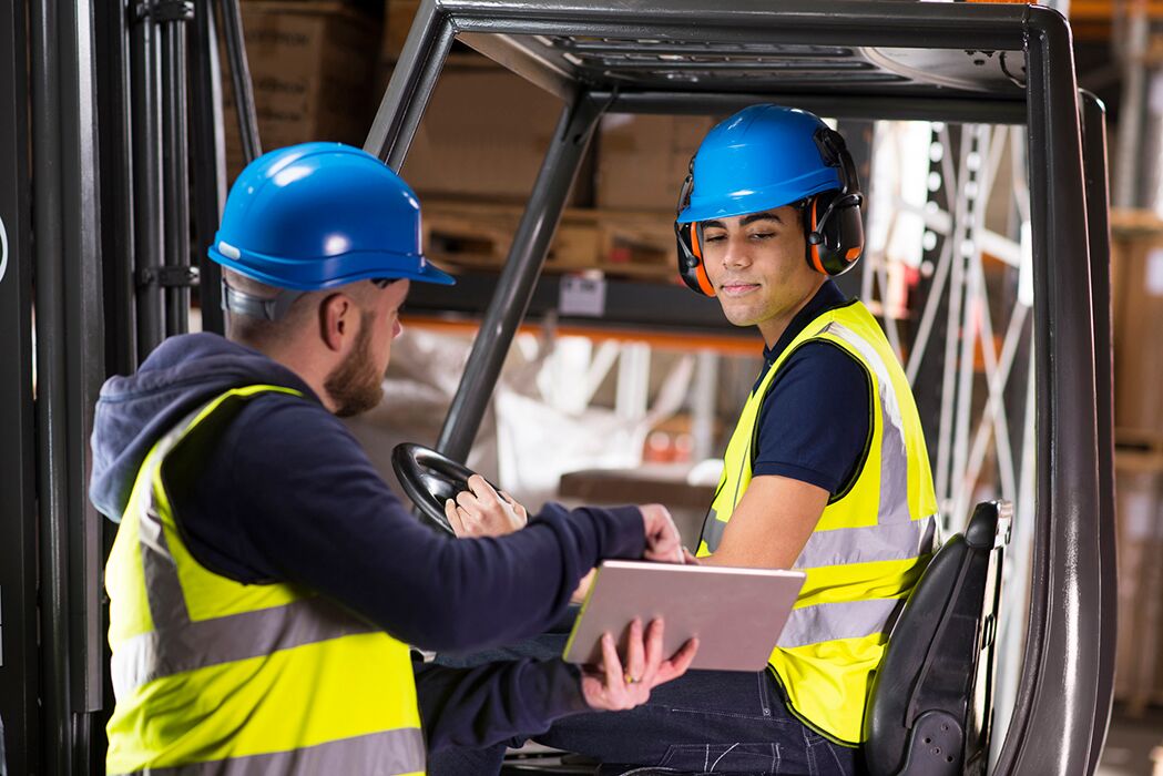 Warehouse manager training employee to use forklift