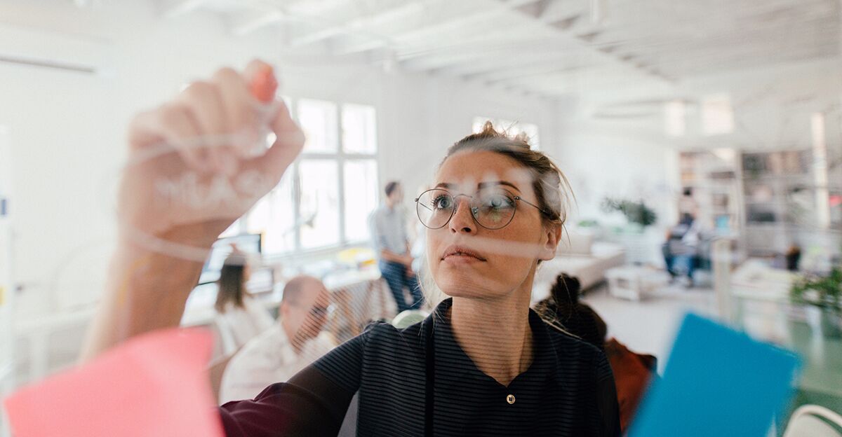 Woman writing on clear whiteboard