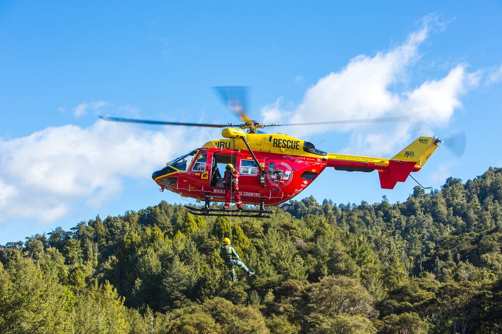 The Westpac Rescue Helicopter flies in front of a forest
