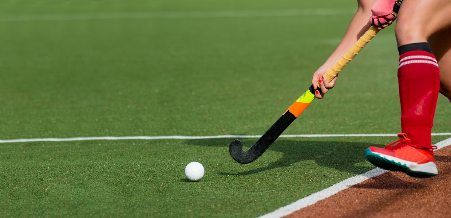 A hockey player hitting a ball on the astroturf