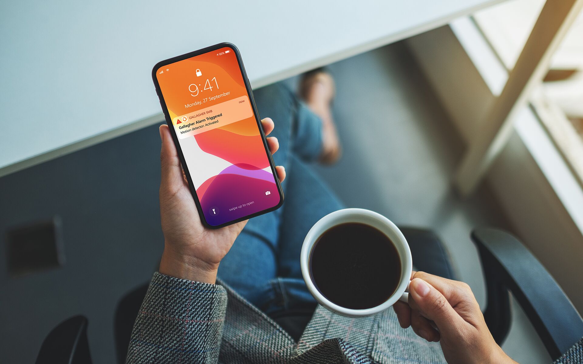 Person checking Gallagher SMB notification on phone while drinking coffee