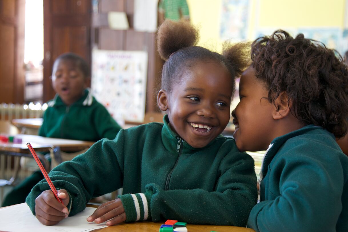 Young schoolgirl whispers to her friend in class, KwaZulu Natal Province, South Africa