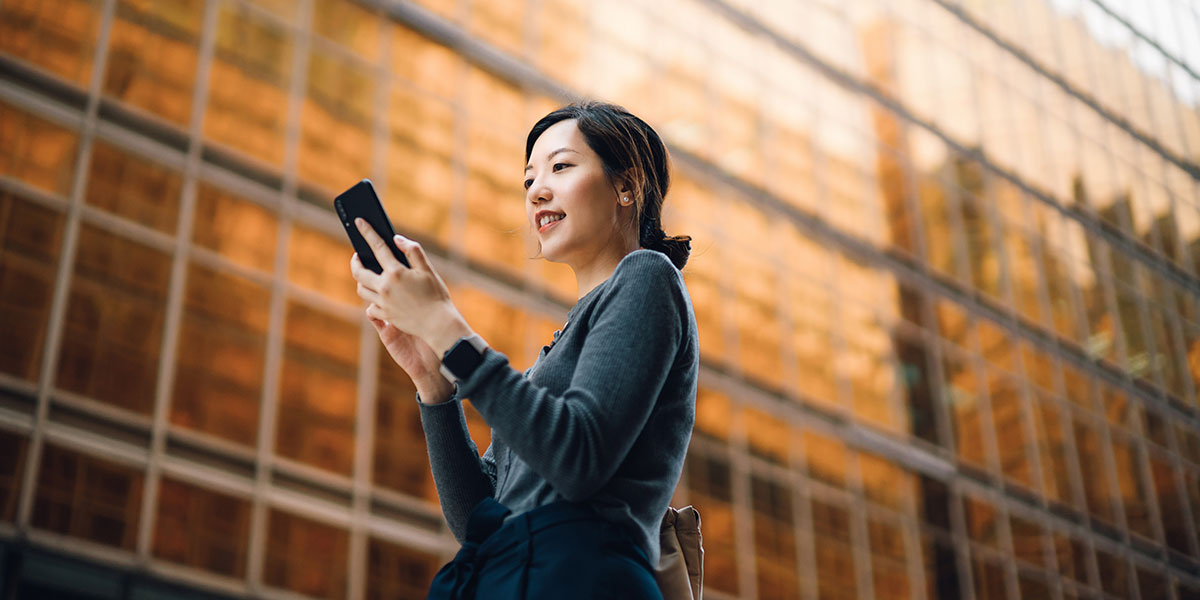 Woman walking near workplace while using mobile device