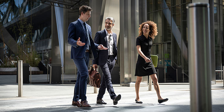 three business people walking into an office building