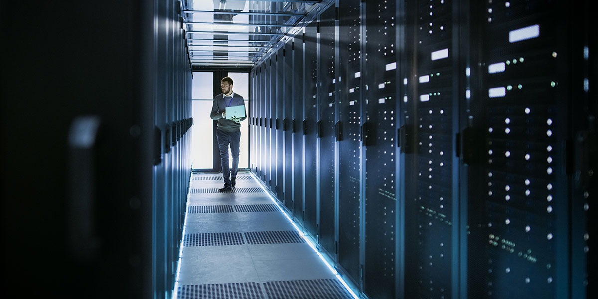 Data center technician walking through data hall with laptop