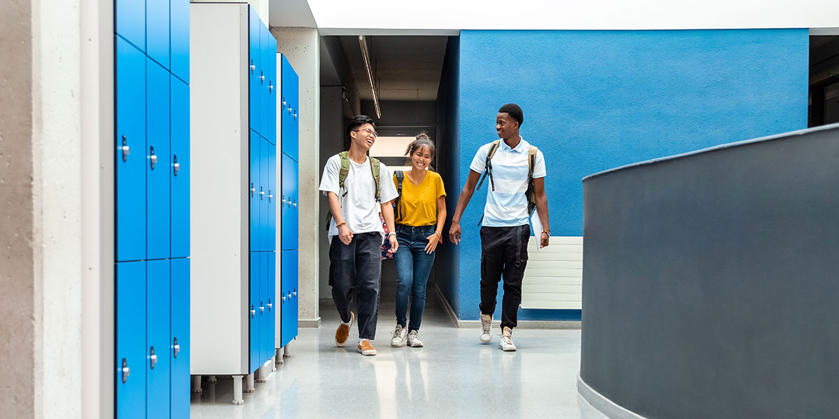 k-12 students walking through a corridor past blue lockers