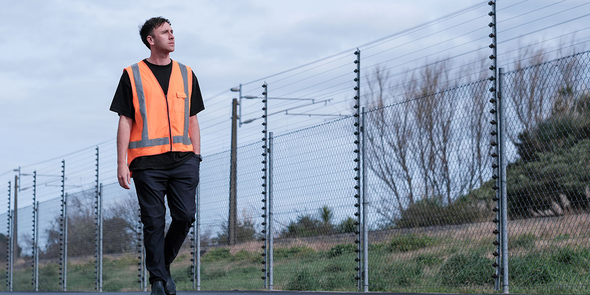 Critical Infrastructure Worker Walking Periemeter Fence Line 