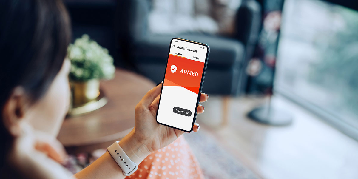 Small business owner looking at security alarm notification on her mobile phone