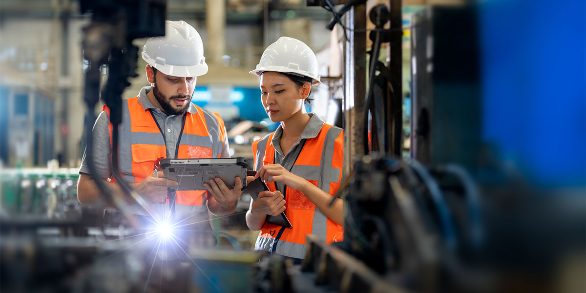 Engineers observing a robotics arm welding units at a manufacturing site