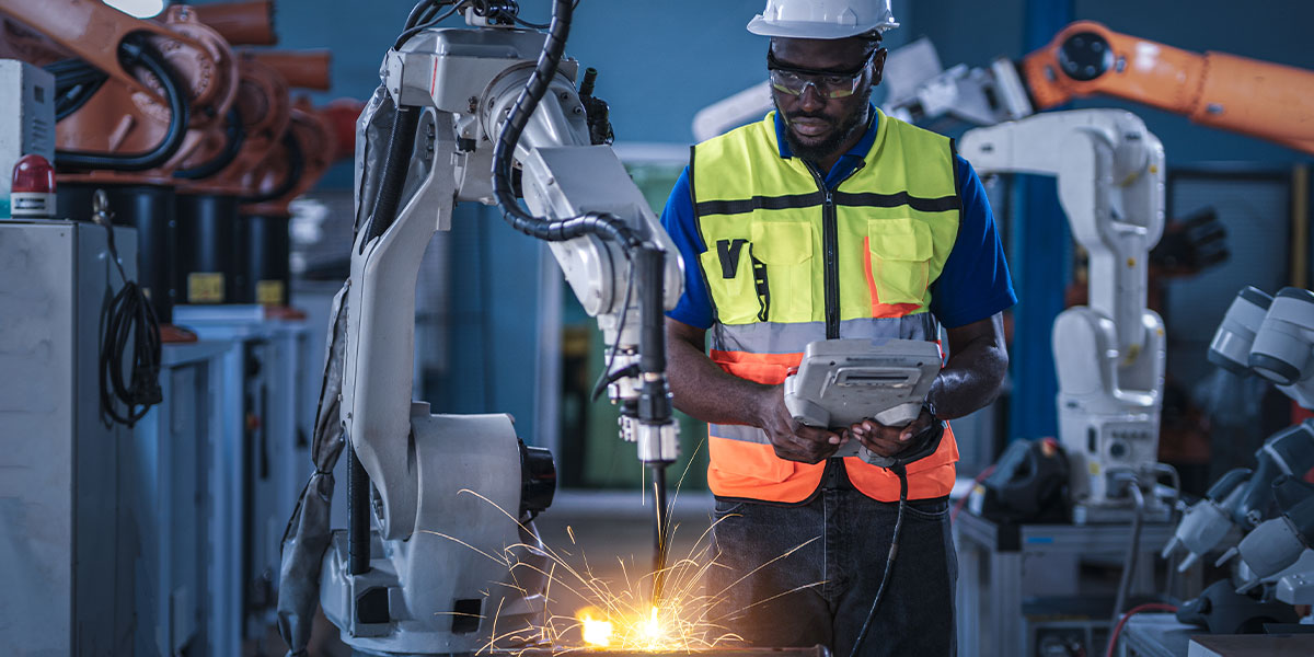 Engineer controlling robotic arm at manufacturing plant