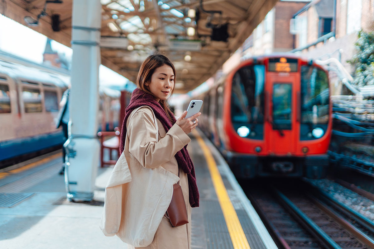 Woman looking at phone while waiting for a train