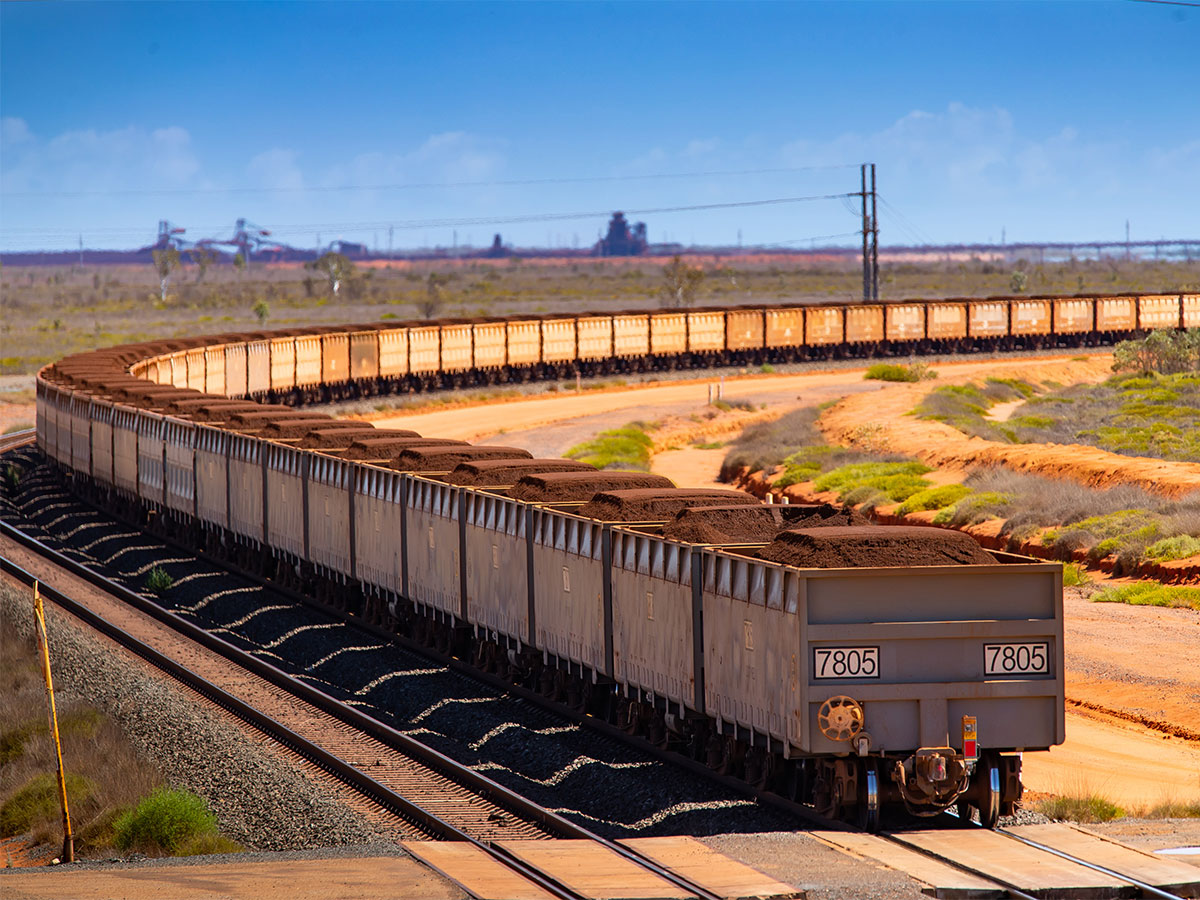 A freight train carrying iron ore travelling along a rail track in Australia