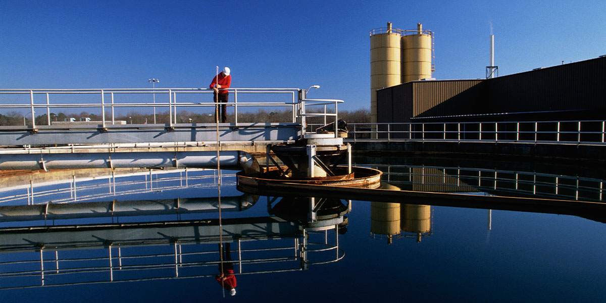 Contractor checks on a treatment pond at a waste water treatment plant