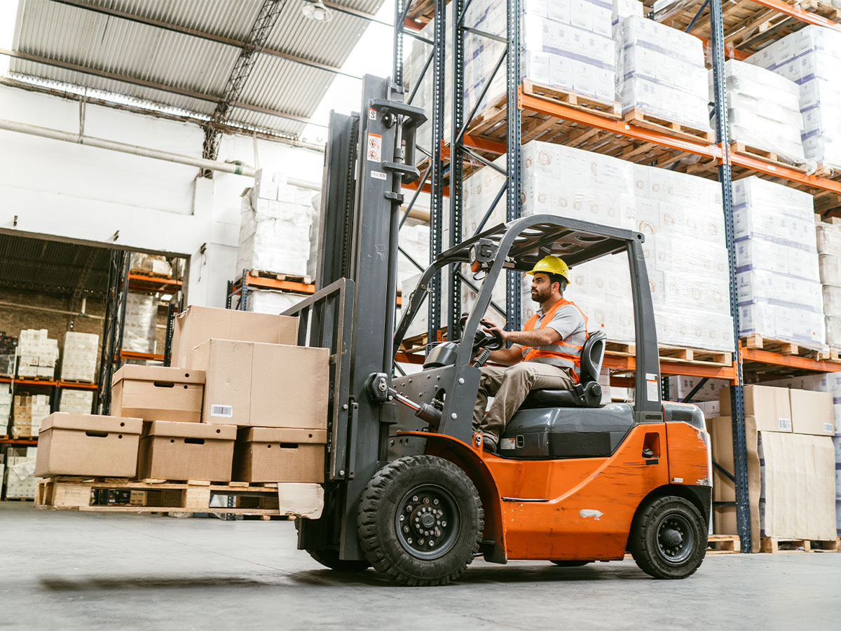 Forklift operator transporting boxes in warehouse